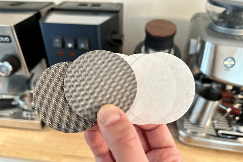 espresso puck screen and paper filters held in front of espresso machines