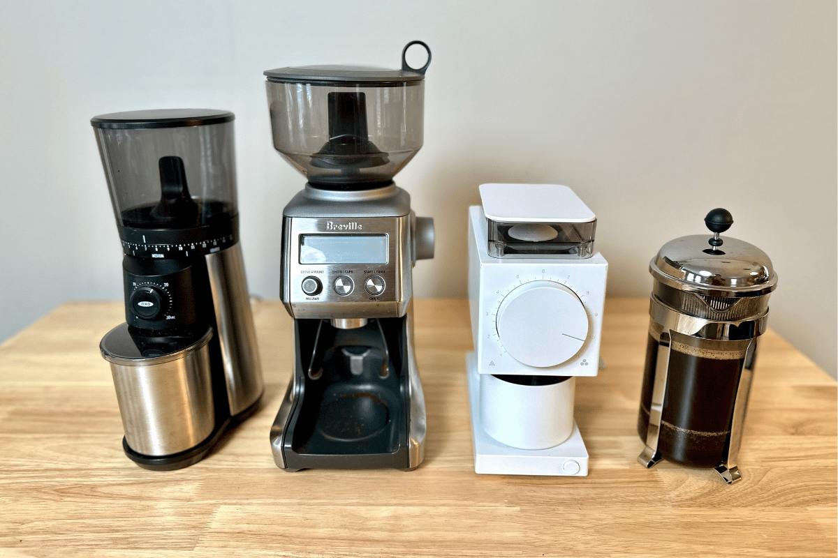 Oxo grinder, Breville Smart Grinder Pro, and Fellow Ode grinder next to French Press coffee